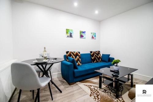 a living room with a blue couch and a table at WEEKLY & MONTHLY STAY - Beautiful 2 Bed House with FREE Parking - Relocation, Business & Group - 5 Guests - By Den Accommodation Short Lets & Serviced Accommodation, Woolwich in Woolwich