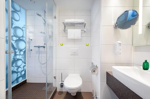 a bathroom with a toilet and a shower and a sink at Holiday Inn Berlin City East Side by IHG in Berlin