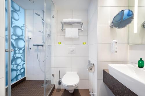 uma casa de banho com um WC, um chuveiro e um lavatório. em Holiday Inn Berlin City East Side, an IHG Hotel em Berlim