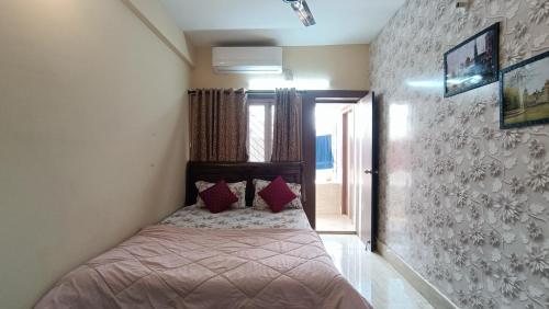Luxurious studio apartment in Newtown في Thākurdwari: غرفة نوم عليها سرير ومخدات حمراء