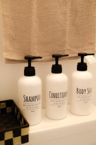 a group of three shampoo bottles on a shelf in a bathroom at Wafu Ryokan Uehonmachi in Osaka
