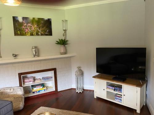 a living room with a flat screen tv on a white cabinet at Chesterfarm and Stables in Willyung
