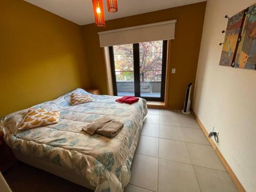 1 dormitorio con 1 cama con 2 almohadas y ventana en Depto en pleno centro de San Martin de los Andes. en San Martín de los Andes