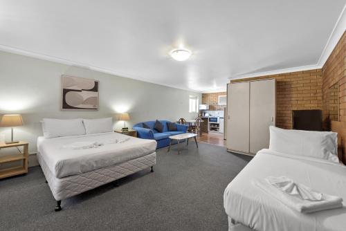 une chambre d'hôtel avec deux lits et un canapé bleu dans l'établissement Paramount Motel, à Brisbane