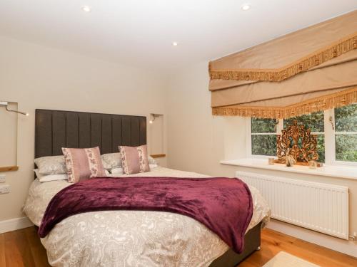 a bedroom with a large bed and two windows at Olive Tree Cottage in Langport
