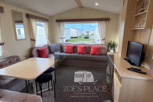 un soggiorno con divano e cuscini rossi di 3 Bedroom 8 Berth cosy static family caravan a Rhyl