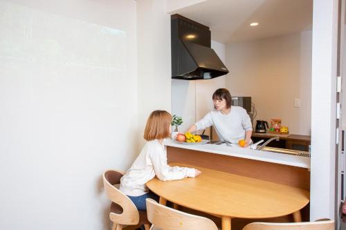 a man and a girl sitting at a table in a kitchen at ゲストルーム心音-金澤表参道- in Kanazawa