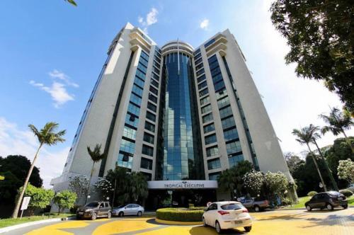 a large building with cars parked in a parking lot at Tropical Executive Hotel N 619 in Manaus