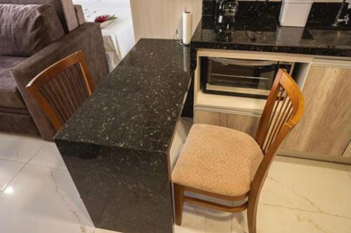 a kitchen with a black counter top and two chairs at Tropical Executive Hotel N 619 in Manaus