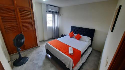 1 dormitorio con 1 cama con almohadas de color naranja en Apartamentos en el Rodadero Sur- Ed San José, en Santa Marta