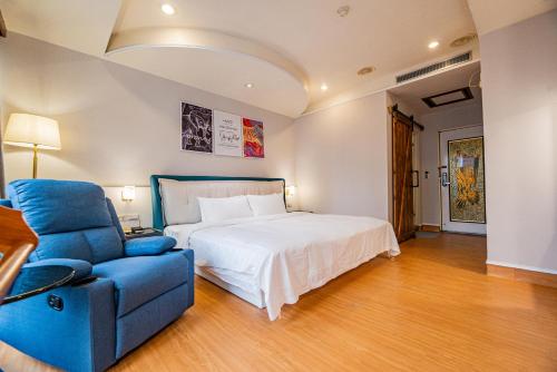 a bedroom with a bed and a blue chair at Wenpin Hotel - Pier 2 in Kaohsiung