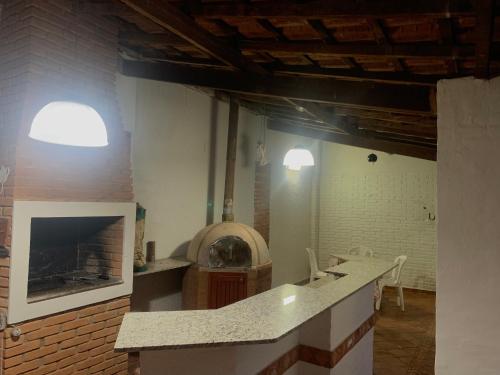 a kitchen with a counter top and a fireplace at Quarto em casa c/piscina in Ouro Fino