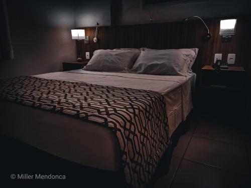 una camera da letto con un grande letto con una lampada di Quarto Executivo para Sua Estadia de Trabalho a Campos dos Goytacazes
