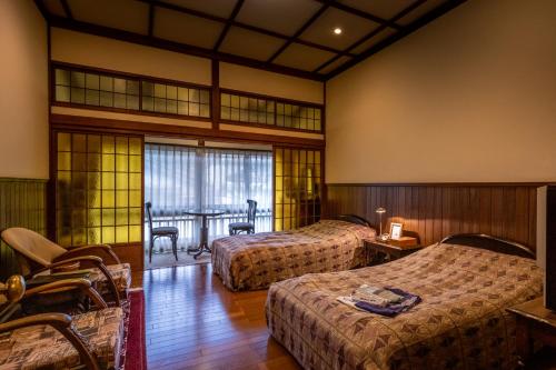 a hotel room with two beds and a table at Hotel Hanakoyado in Kobe