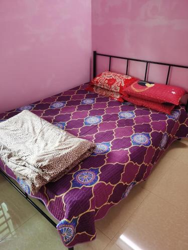 a bed with a purple comforter and pillows on it at Homestay Che Wan Dua in Kuantan