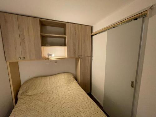 - une petite chambre avec un lit et des placards en bois dans l'établissement Appartement proche plage avec piscine, parking et animaux admis - FR-1-413-215, à Capbreton
