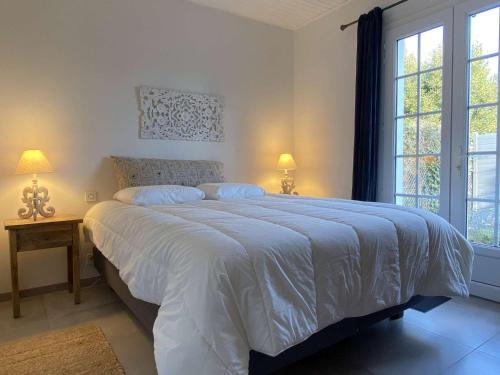 une chambre avec un grand lit blanc avec deux lampes dans l'établissement Maison calme proche plage avec jardin et wifi, 4 couchages à La Brée-les-Bains - FR-1-246A-214, à La Brée-les-Bains