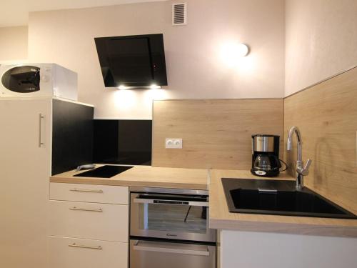 une cuisine avec un évier et une cuisinière four supérieur dans l'établissement Charmant T2 avec balcon, parking privatif, idéalement situé au Mont-Dore, proche centre et thermes - FR-1-608-244, à Le Mont-Dore