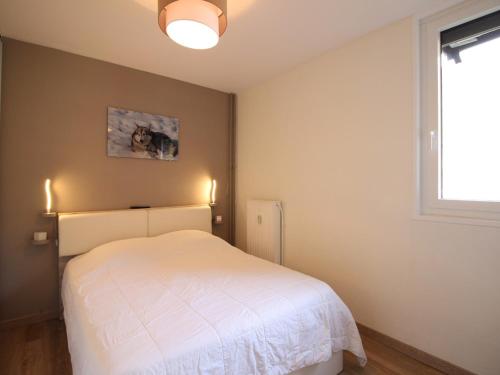 une chambre avec un lit blanc et une fenêtre dans l'établissement Charmant T2 avec balcon, parking privatif, idéalement situé au Mont-Dore, proche centre et thermes - FR-1-608-244, à Le Mont-Dore