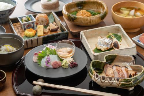 una mesa con platos de comida y tazones de comida en Hotel Hanakoyado, en Kobe