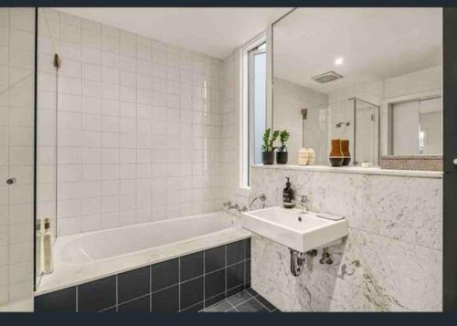 uma casa de banho com uma banheira, um lavatório e um espelho. em Modern South Melbourne Town House. em Melbourne