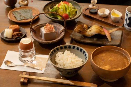 a wooden table topped with bowls of food and rice at Hotel Hanakoyado in Kobe