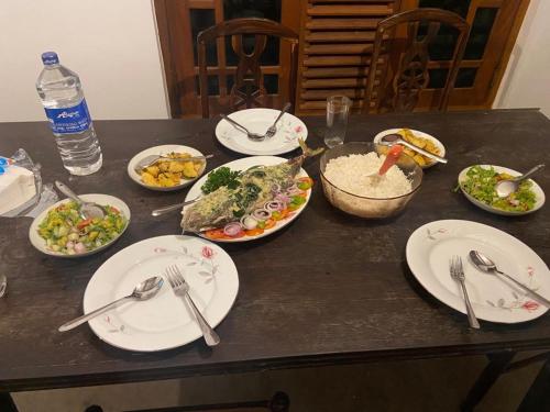a table with plates of food and forks and spoons at Surf Forever in Midigama