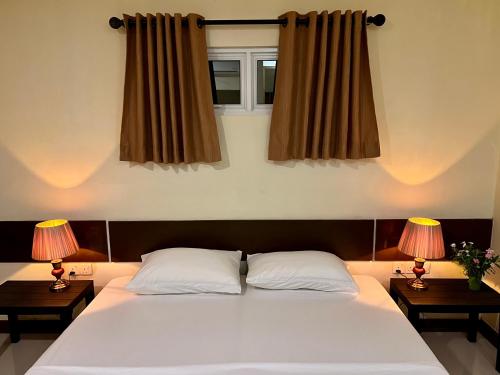 um quarto com uma grande cama branca e 2 candeeiros em Athiri Inn Kelaa em Kelaa