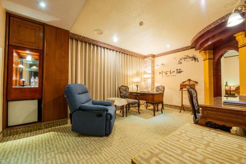 a living room with a blue chair and a table at Wenpin Hotel - Pier 2 in Kaohsiung