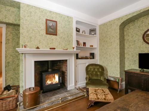 a living room with a fireplace and a chair at Kylemore in Glastonbury