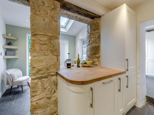 a kitchen with white cabinets and a stone wall at Ivy Mount in Uny Lelant