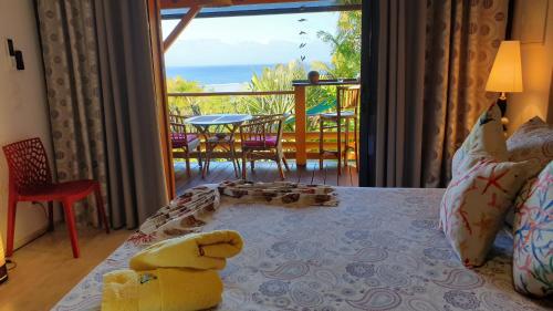 a teddy bear sitting on a bed in a room with a balcony at Poz Lagon - chambre d'hôtes - Bungalow pour 2 personnes - Jacuzzi privatif - petit déjeuner - Vue sur le lagon in La Saline les Bains