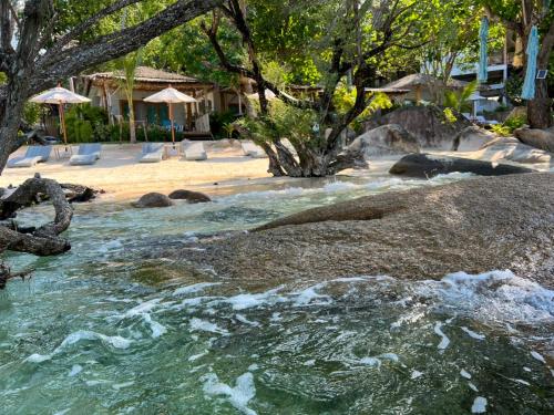 a pool of water next to a resort with trees at Siam Cookies Cottage in Haad Pleayleam
