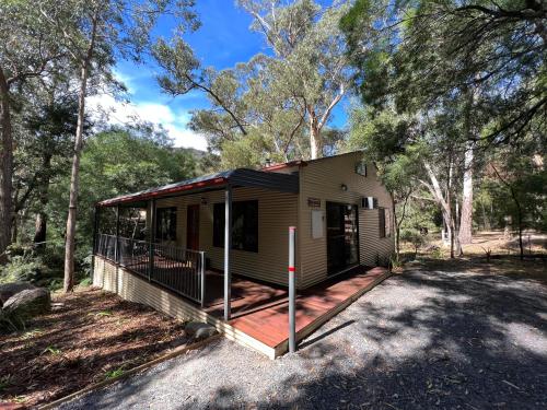 a small house with a deck in the woods at The Kingfisher Lodge 111 in Halls Gap