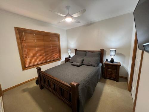 a bedroom with a bed with a ceiling fan and a window at The Kingfisher Lodge 111 in Halls Gap