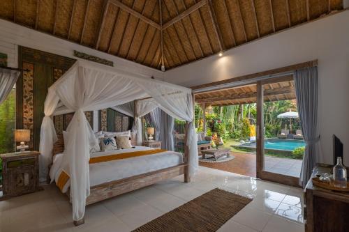 1 dormitorio con cama con dosel y piscina en The Gardener's Cottage, en Ubud