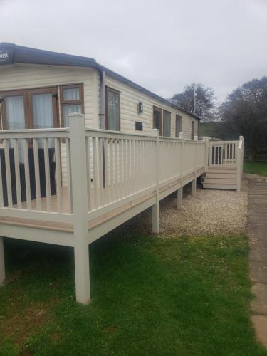 a mobile home with a porch and white railings at CCT Caravan in Turnberry