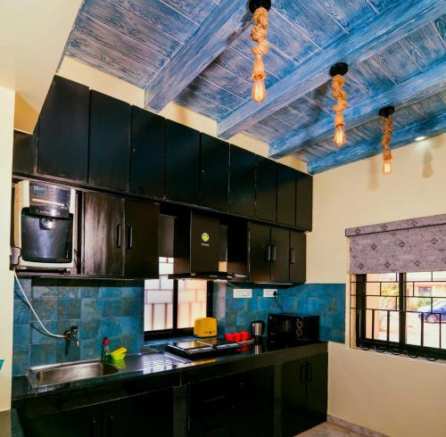 a kitchen with black cabinets and a blue ceiling at 'Golden Sea Pearl' 1 bhk Beach apartment in Benaulim