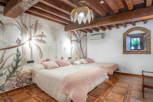 1 dormitorio con 2 camas y lámpara de araña en Apartamentos La Solana de Monfragüe, en Malpartida de Plasencia