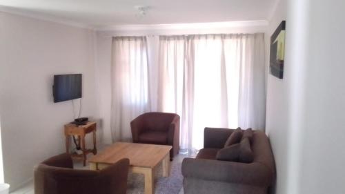 a living room with a couch and chairs and a table at Broadway Self Catering Apartments in Durbanville