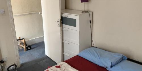 ロンドンにあるRooms To Let In Londonのベッド1台、冷蔵庫が備わる小さな客室です。