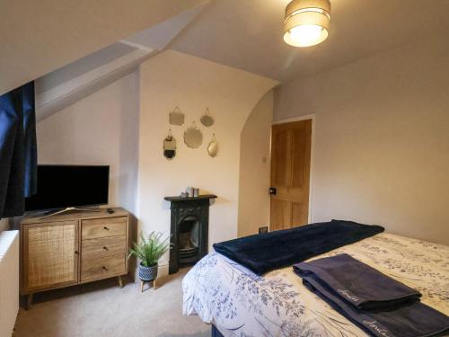 a bedroom with a bed and a tv and a fireplace at Bumblebee Cottage in Beverley