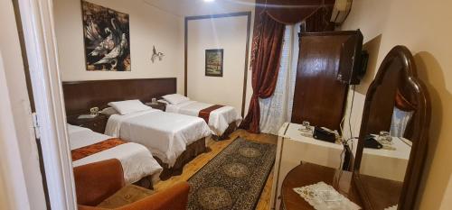 een hotelkamer met 2 bedden en een spiegel bij Misr Hotel in Alexandrië