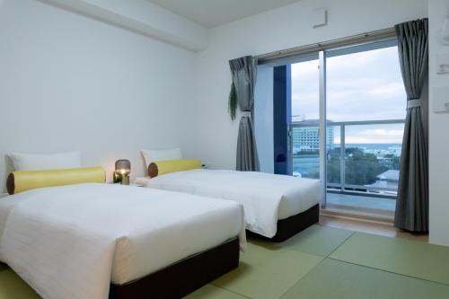 una camera d'albergo con due letti e una grande finestra di クリスタルエグゼ南紀白浜2 a Shirahama