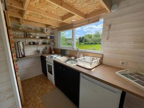 a kitchen in a tiny house with a sink and a window at Tiny house au cœur du bocage in Landelles-et-Coupigny