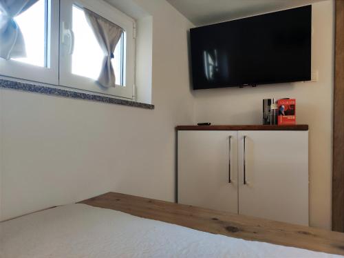 een slaapkamer met een flatscreen-tv aan de muur bij apartman Emili in Malinska