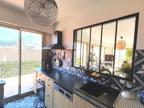 - une cuisine avec un comptoir noir et de grandes fenêtres dans l'établissement Appartement 90m2, climatisé 3 chambres, à Nice