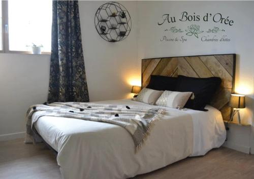 una camera da letto con un grande letto bianco con un cartello sul muro di AU BOIS D'ORÉE a Liré