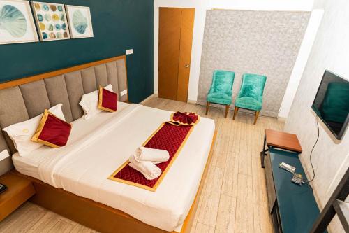 a hotel room with a bed with two chairs at Hotel Aalia in Thanjāvūr