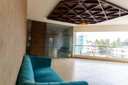 a living room with a blue couch and a balcony at Hotel Aalia in Thanjāvūr